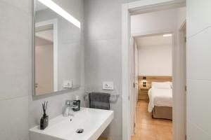 a bathroom with a sink and a mirror and a bed at S Q Playa de Sardina in Gáldar +15 photos