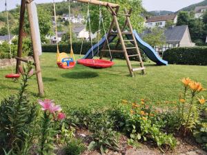 a playground with swings and flowers in a yard at Ferienwohnung Am Kamp in Schmallenberg