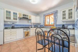 a kitchen with white cabinets and a table and chairs at Solluna in Son Servera