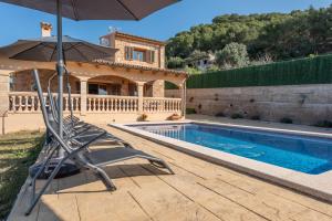 a pool with chairs and an umbrella next to a house at Solluna in Son Servera