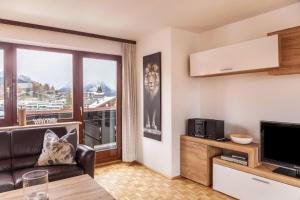 a living room with a couch and a large window at Haus Excelsior Top 21 in Seefeld in Tirol