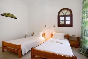 two twin beds in a room with a window at Areti Orfeas Apartment 6 in Vasilikos
