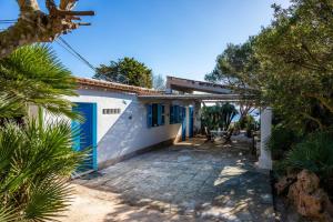 a white house with a blue door and trees at Finca Es Carregador in Capdepera
