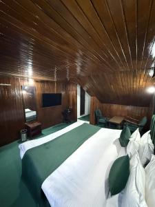 a bedroom with a large bed with a wooden ceiling at Riverdale by Stay Pattern in Pahalgām