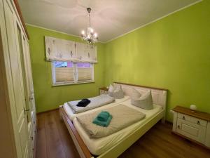 a bedroom with a bed with green walls and a window at Ferienhaus Weitblick in Zossen