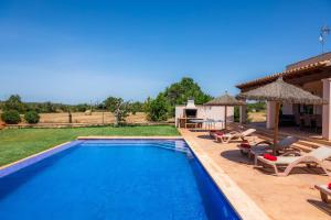 a pool with chairs and umbrellas in a yard at Sa Xorca in Santanyi