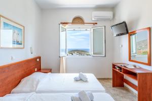 a bedroom with a bed and a tv and a window at Anemologio 304 Tinos in Agios Ioannis