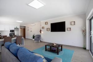 a living room with a couch and a tv on a wall at Villa Flor Rosa Piscina e Jacuzzi in Salir de Matos