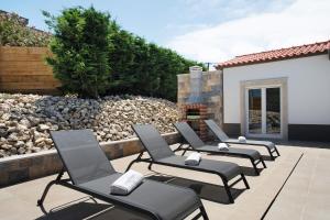 a row of chairs sitting on a patio at Villa Flor Rosa Piscina e Jacuzzi in Salir de Matos