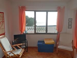 a living room with a window and a chair and a television at Apartament Bouganville in Alaior