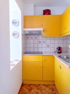 a kitchen with yellow cabinets and a sink at Apartament Bouganville in Alaior