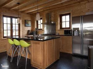 a kitchen with green bar stools and a refrigerator at Houten Villa Dirk in Den Ham