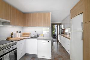 a kitchen with white appliances and wooden cabinets at Vilamoura com Piscina e Wifi in Vilamoura