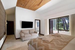 a bedroom with a bed and a couch and a tv at Vilamoura com Piscina e Wifi in Vilamoura