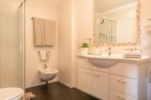 a white bathroom with a sink and a toilet at Kristiania Apartement Typ A1 in Siusi +21 photos