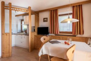 a kitchen and dining room with a white table and chairs at Kristiania Apartement Typ A1 in Siusi