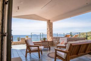 a patio with chairs and a view of the ocean at Villa Coral Bay in Alghero
