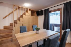 a dining room with a wooden table and blue chairs at Ciasa Willy App Conturines in La Villa