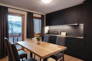 a kitchen and dining room with a wooden table at Ciasa Willy App Conturines in La Villa +22 photos