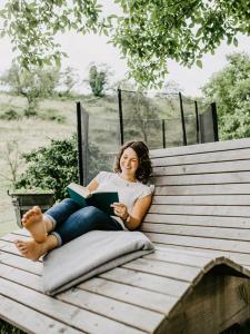 a woman sitting on a bench reading a book at Schlossberghof Schnellingen in Haslach im Kinzigtal