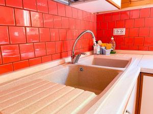 a kitchen with a sink and a red tiled wall at Le sorgenti - Chalet 12 in Palazzuolo sul Senio +29 photos