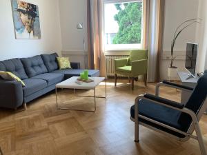 a living room with a blue couch and chairs at Bodenseeloft H E 66 in Kressbronn am Bodensee