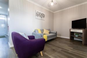 a living room with a purple couch and a tv at Oásis Fonte Grande in Santo António
