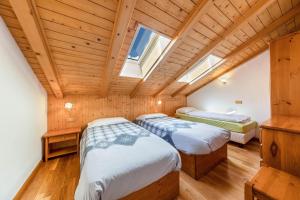two beds in a room with wooden ceilings at Ciasa Sommavilla Mansarda in Vigo di Fassa