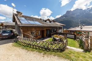 a house in the mountains with a car parked next to it at Ciasa Sommavilla Mansarda in Vigo di Fassa