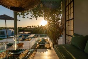 a dining table on a patio with the sun setting at Villa Celeste-Essaouira, piscine chauffée, vue sur la campagne in Essaouira