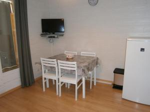 a dining room table with white chairs and a tv at Studio Les Fontettes 2 in Le Dévoluy
