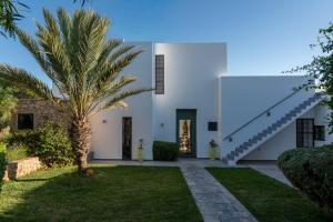 a palm tree in front of a white house at Villa Celeste-Essaouira, piscine chauffée, vue sur la campagne in Essaouira