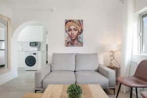 a living room with a couch and a painting of a woman at Piso Acogedor Tarifa Centro in Tarifa