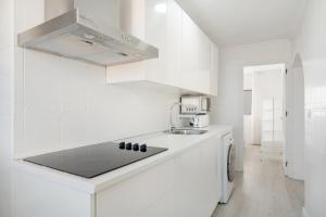 a white kitchen with a sink and a microwave at Piso Acogedor Tarifa Centro in Tarifa +11 photos