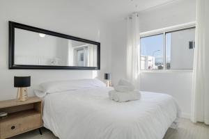 a white bedroom with a large bed with a mirror at Piso Acogedor Tarifa Centro in Tarifa