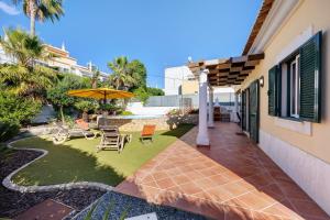 a backyard with a patio with an umbrella and chairs at Villa Tucha in Alvor