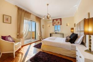 a bedroom with a bed and a chair and a window at Villa Tucha in Alvor +35 photos