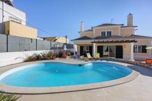 a swimming pool in front of a house at Villa Tucha in Alvor