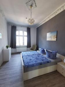 a bedroom with a blue bed and a chandelier at Villa Adler- Seeseite in Ahlbeck