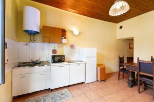 a kitchen with white cabinets and a table and a refrigerator at Quadrifoglio House in Ameno +12 photos