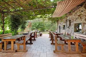 a row of wooden tables and benches in a patio at chalet nel bosco in Casarza Ligure