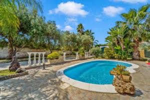 a swimming pool in a yard with palm trees at Villa Angela in Quartu SantʼElena