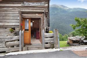 an open door of a wooden cabin with a fence at Taulain Gotrosio in Valdisotto