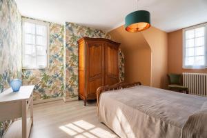 a bedroom with a bed and a cabinet and windows at Maison De Caractère in Cancale