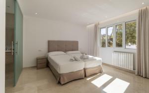 a white bedroom with a large bed and a window at Can Luciana in La Aranjasa +19 photos