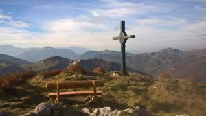 a wooden cross on top of a hill with a bench at Les Silenes in Bellevaux +2 photos