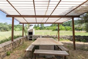 a picnic table under a roof with a stone wall at Villa La Barbière in Sallelles