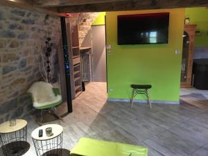 a living room with a green wall with a tv at Cocoon,Vue Montagne,Jacuzzi privé in Mostuéjouls