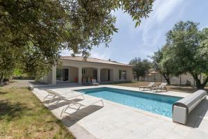 a swimming pool with chairs and a house at Villa La Barbière in Sallelles