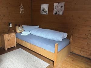 a bed in a wooden room with a night stand at Ferienwohnung Herzogenhorn in Bernau im Schwarzwald